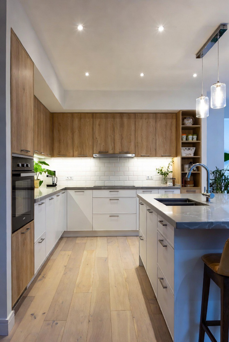 Cuisine après rénovation : façades bois et laque blanche, îlot et plan de travail en pierre